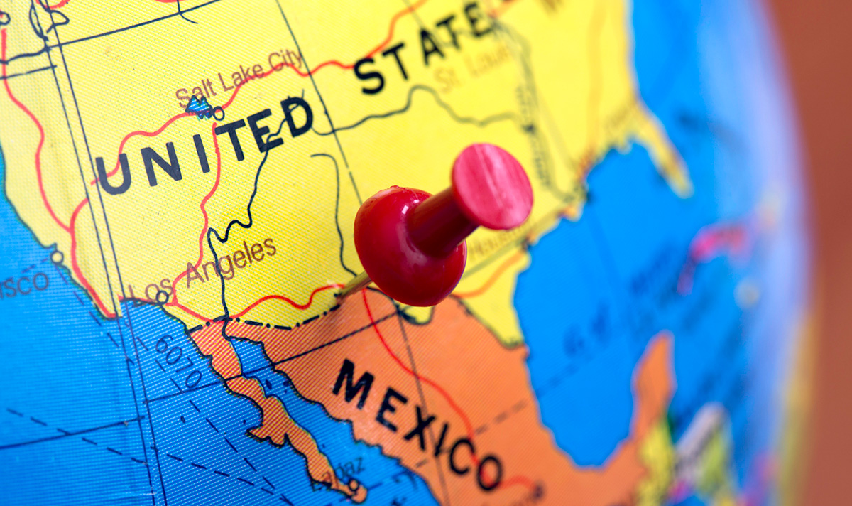 A red pushpin marking the U.S.-Mexico border on a globe