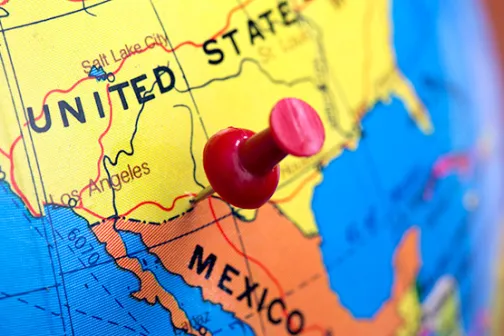 A red pushpin marking the U.S.-Mexico border on a globe